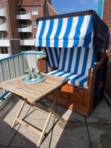 a blue and white striped chair and a table on a balcony at Strandläufer in Cuxhaven