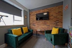 拉姆斯蓋特的住宿－Albert's Watch，客厅设有两张绿色沙发和砖墙