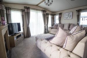 a living room with a couch and a television at Beautiful Lodge At Manor Park In Hunstanton Ref 23018k in Hunstanton