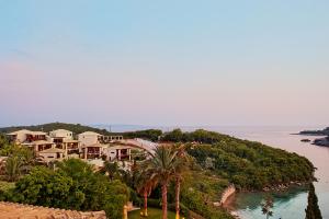 a house on a hill next to a body of water at Ornella Beach Resort & Villas in Syvota