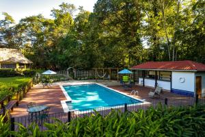 a swimming pool with a deck and a house at Tanager RainForest Lodge in Big Falls