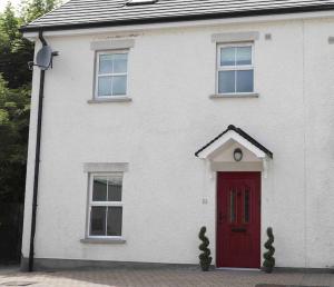 a white house with a red door and two windows at 4 Castle Court in Enniskillen