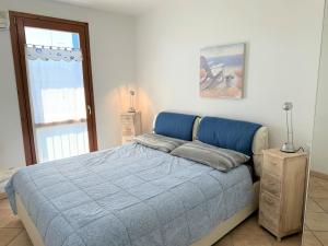Un dormitorio con una cama azul y una ventana en Porto Antico Village, en Aprilia Marittima