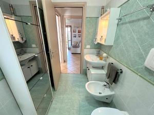 La salle de bains est pourvue de toilettes, d'un lavabo et d'un miroir. dans l'établissement Porto Antico Village, à Aprilia Marittima