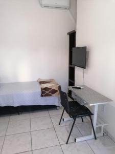 a bedroom with a bed and a desk with a computer at Quarto para Rapazes no Centro Sinop MT in Sinop