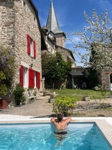a man in a swimming pool in front of a building at Le couvent de Jouels in Sauveterre-de-Rouergue