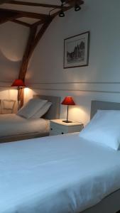 a bedroom with two beds and two lamps on tables at AU MANOIR DE LA BARRE in La Barre-en-Ouche