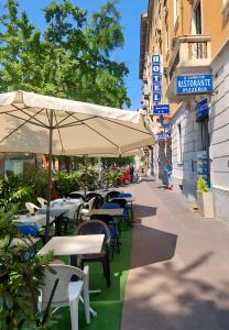 una cafetería al aire libre con mesas, sillas y sombrilla en Hotel Aurelia Milano Centrale, en Milán