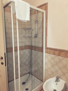 um chuveiro com uma porta de vidro ao lado de um lavatório em Residenze l'Alberata em Collazzone