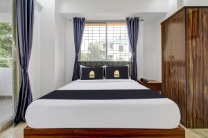 um quarto com uma cama grande e uma janela em Townhouse OAK Red Velvet Suites & Inn Koregoan Park em Pune
