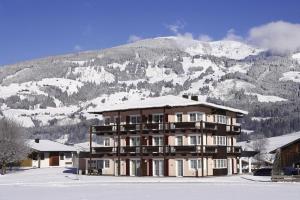duży budynek przed pokrytą śniegiem górą w obiekcie Sonnblick Apartments und Zimmer - Nationalpark Sommercard inklusive w mieście Hollersbach im Pinzgau