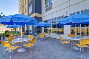 a patio with tables and chairs with blue umbrellas at Fairfield Inn & Suites by Marriott Kamloops in Kamloops