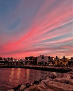 una puesta de sol sobre un cuerpo de agua con edificios en La stradina, en Mola di Bari