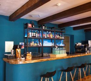 un bar con taburetes en una habitación con una pared azul en HOTEL ST SEBASTIEN en Roquebillière