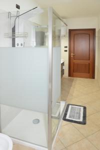 y baño con ducha de cristal y puerta de madera. en Casa Vacanza Il Dolce Mare, en Alghero