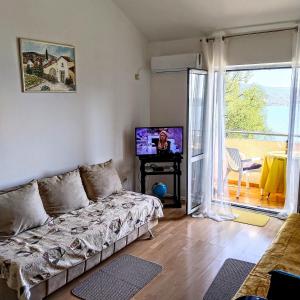 ein Wohnzimmer mit einem Sofa, einem TV und einem Balkon in der Unterkunft Apartments "Belle Vue" in Herceg-Novi