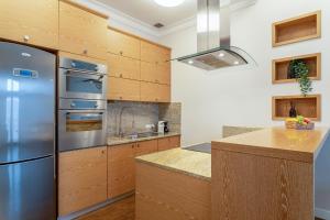 une cuisine avec un réfrigérateur en acier inoxydable et des armoires en bois dans l'établissement Historic Market Square Suite -140m2 Grand Residence AS Home Apartamenty R504, à Wrocław 16 autres photos