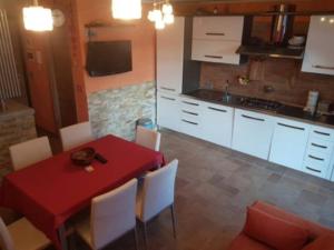 a kitchen with a red table and white cabinets at Valtournenche EVETTE in Valtournenche