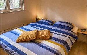 een bed met blauwe en witte gestreepte lakens en kussens bij Lovely stacaravan In Markelo With Wifi in Markelo