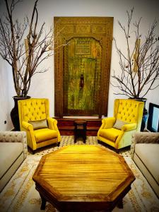 uma sala de estar com duas cadeiras amarelas e uma mesa em Riad Soir De Marrakech em Marrakech
