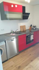 uma cozinha com armários vermelhos, um lavatório e uma máquina de lavar louça em EXCLUSIVES TOP-Apartment in traumhafter Aussichtslage WLAN kostenfrei em Schöfweg