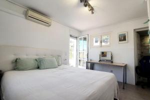 Habitación blanca con cama grande y escritorio. en Villa Oasis 10 pers, piscina, BBQ, 10 min playa, en El Tosalet