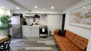 Renovated Guest Suite Near The Lake & High Park in Toronto! في تورونتو: غرفة معيشة مع أريكة ومطبخ
