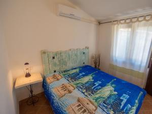 a bedroom with a bed with a blue comforter and a table at Appartamento Santa Maria Porto Pollo in Palau