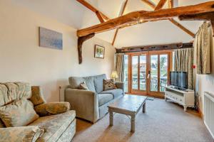 a living room with a couch and a tv at PondView Cottage with swimming pool, and garden in Tibenham