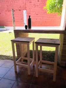 ein Holztisch und zwei Bänke neben einer Ziegelwand in der Unterkunft "Village" Amplia CASA boutique con parrilla y 2 garages in Corrientes