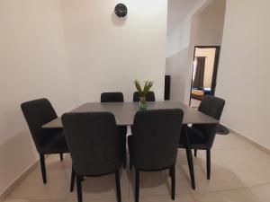 Afna Home stay في كوالا ليبيس: طاولة طعام مع كراسي و إناء من الزهور عليه