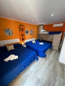 2 łóżka w pokoju z niebieską pościelą i pomarańczowymi ścianami w obiekcie Verde Mare w Trapani
