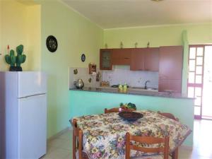 uma cozinha com uma mesa e um frigorífico branco em Villa Selene "Jole" em Ioppolo