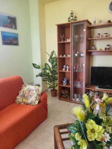 uma sala de estar com um sofá laranja e uma televisão em Villa Selene "Jole" em Ioppolo