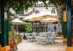 un patio con tavoli, sedie e ombrelloni di Hotel Bahía Olivo Boutique & Spa a Villa de Leyva
