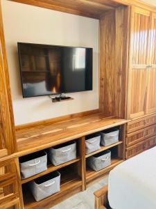 a room with a television on a wooden entertainment center at Ocean Breeze in Placencia Village