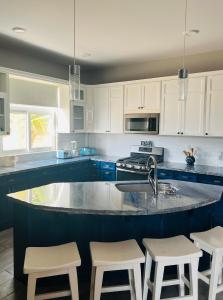 a kitchen with white cabinets and a large island with stools at Ocean Breeze in Placencia Village