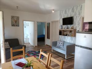 a kitchen and living room with a table and a refrigerator at Liget Vendégház in Szokolya