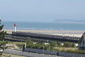 a bridge over a beach with a red lighthouse at Les Embruns - Plein ciel - appartement 3eme étage in Deauville