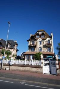 a large building with a white fence in front of it at Les Embruns - Plein ciel - appartement 3eme étage in Deauville
