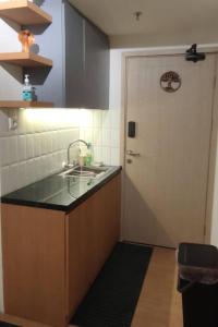 a kitchen with a sink and a white door at Schnucki Studio - JP Apartment in Kedungbadak