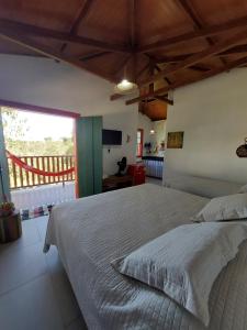 a bedroom with a large bed and a large window at Chalés Vila das Cachoeiras in Diamantina