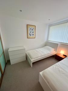 Habitación blanca con 2 camas y ventana en Beautiful modern sea-side apartment in the city, en Edimburgo