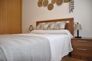 a bedroom with a white bed with a wooden headboard at Alojamiento Santa Maria Bertamirans in Ortoño