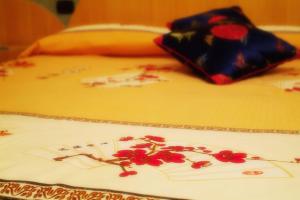 a bed with a yellow blanket with red flowers on it at Hotel Bengasi in Moncalieri