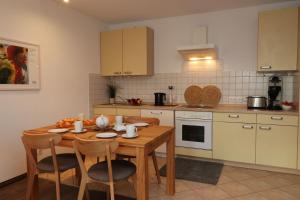 a kitchen with a wooden table with chairs and a kitchen with white appliances at Altes Wasserwerk App 21 in Wustrow +7 photos