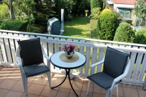 two chairs and a table with a vase of flowers on a balcony at Haus Clarissa, App 02 in Wustrow