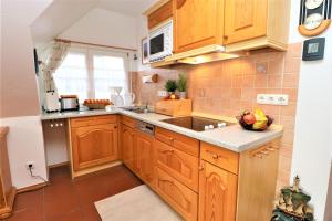a small kitchen with wooden cabinets and a sink at Haus Clarissa, App 02 in Wustrow +6 photos