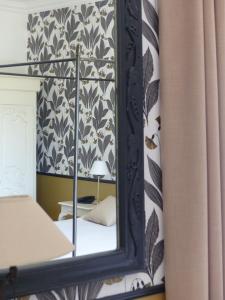 um espelho num quarto com uma cama e um candeeiro em Hostellerie du Château des Fines Roches em Châteauneuf-du-Pape