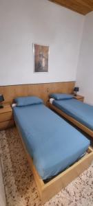 two beds in a room with blue sheets at Casa Leonardo & Elisa in Figline Valdarno